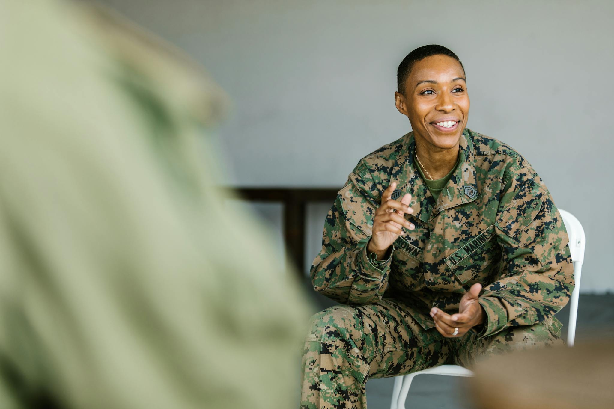 A joyful soldier in uniform participates in a supportive group session indoors.
